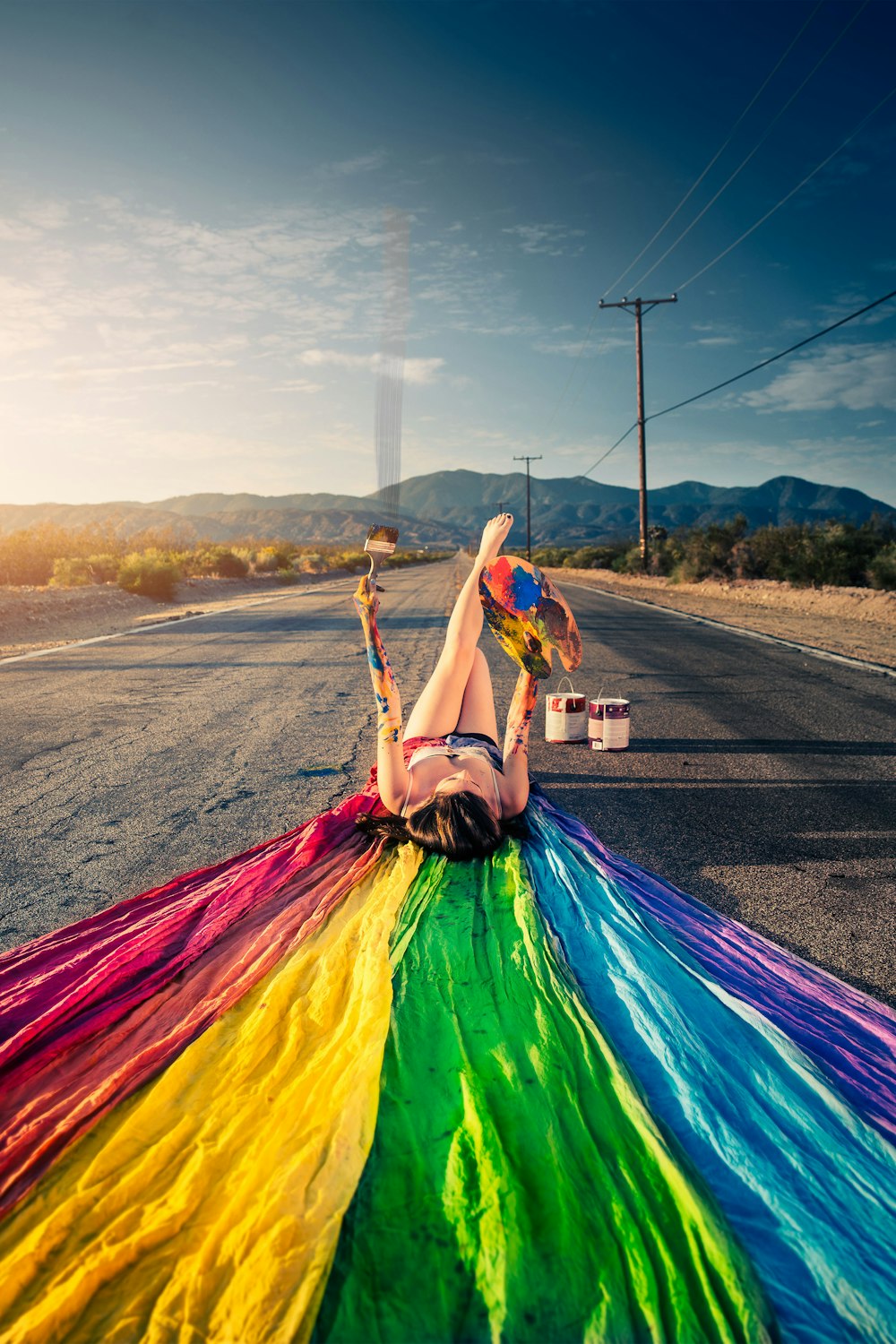 woman lying on road with multicolored textile during daytime