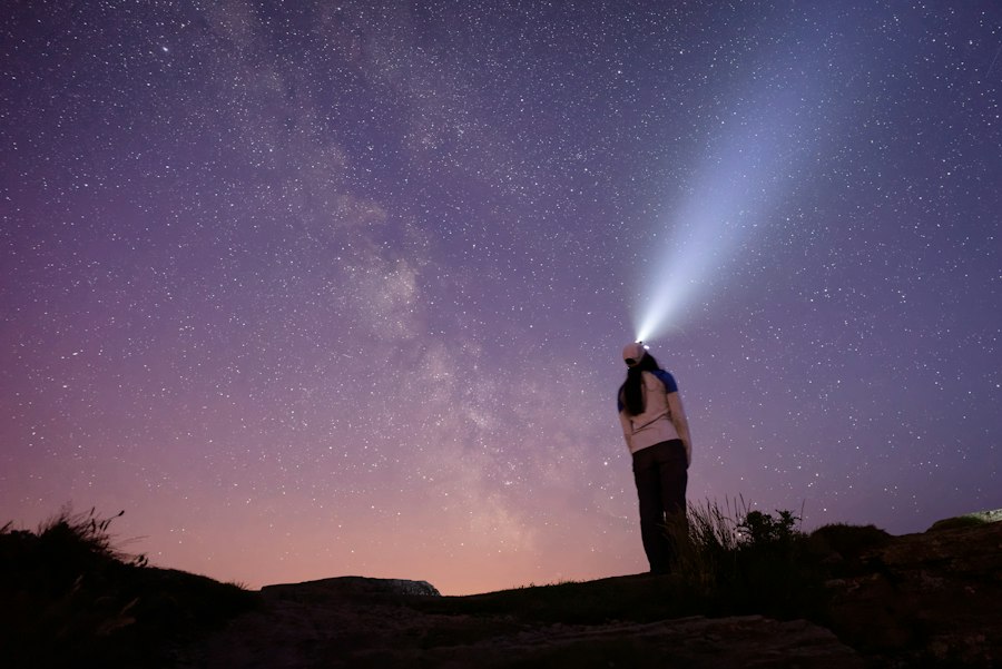 Woman wearing a headlamp at night on a hilltop