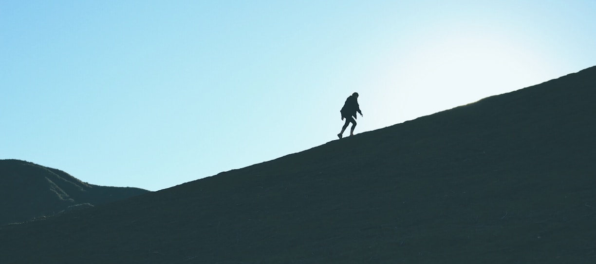 silhouette of man climbing hill