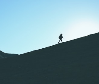 silhouette of man climbing hill