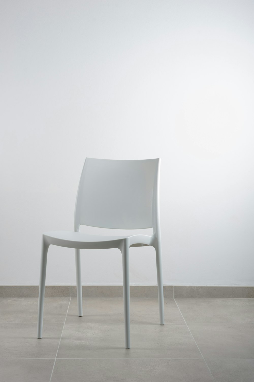 weißer armloser Stuhl in der Nähe einer weißen Wand