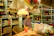 A smiling woman holding a basket filled with colorful Indian spices and fresh produce inside a warmly lit grocery store.