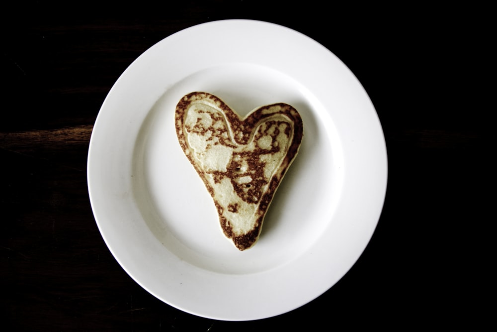 pão torrado em forma de coração em placa redonda de cerâmica branca