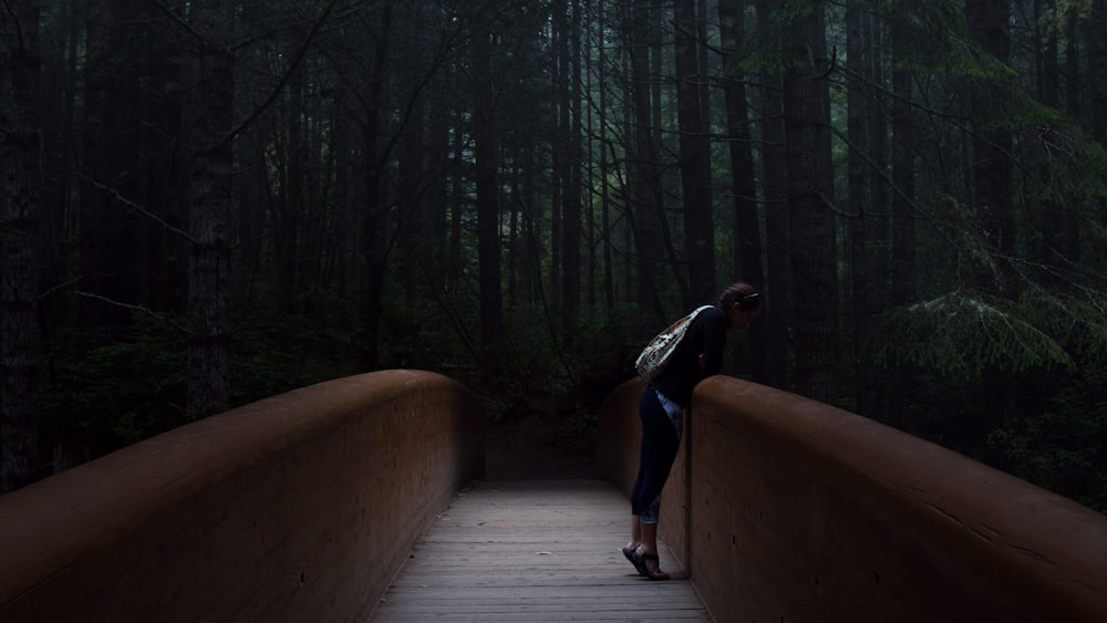 woman standing on brown bridge leaning forward