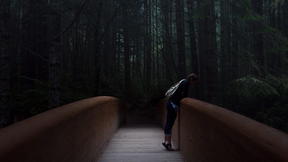 Mujer de pie en el puente marrón inclinada hacia adelante
