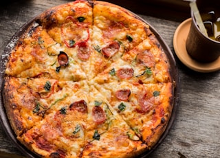 top view photo of pepperoni pizza beside brown cup filled with yellow liquid and ice cubes