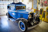 Vintage blue sedan with polished chrome details in a rustic garage.