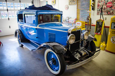 Vintage blue sedan with polished chrome details in a rustic garage.