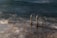 Stainless steel handrails leading into the ocean, with waves gently crashing against a concrete platform. The scene is captured during twilight, adding a mysterious and serene ambiance.