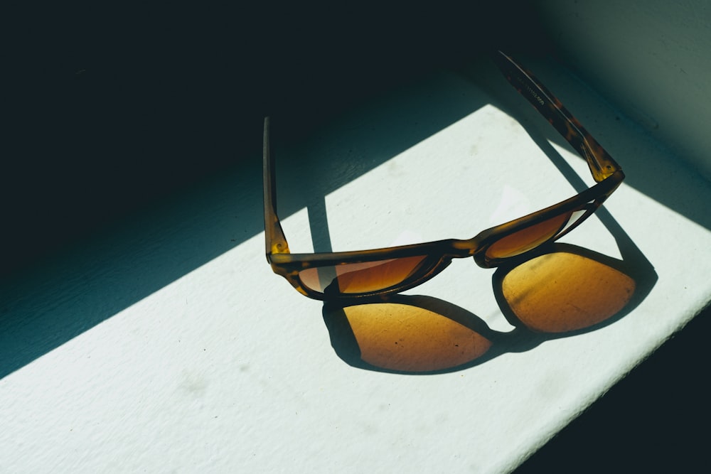 Sonnenbrille mit braunem Rahmen auf weißer Oberfläche
