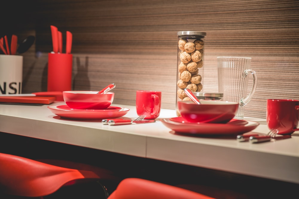 nuts in glass container near red ceramic cups and plates