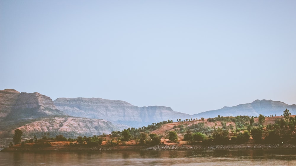 body of water near mountain at daytime