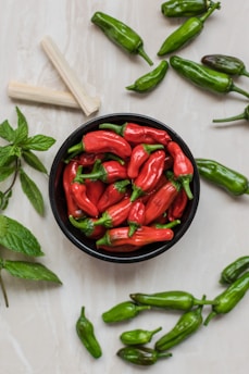 close-up photography of red bell peppers surrounded by green bell peppers