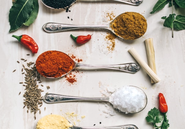 five gray spoons filled with assorted-color powders near chilli