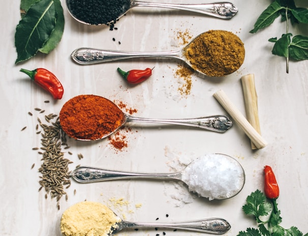 five gray spoons filled with assorted-color powders near chilli