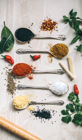 five gray spoons filled with assorted-color powders near chilli