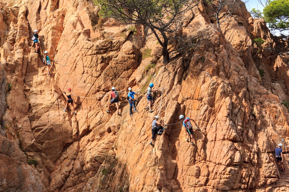 people climbing mountain under sunny sky