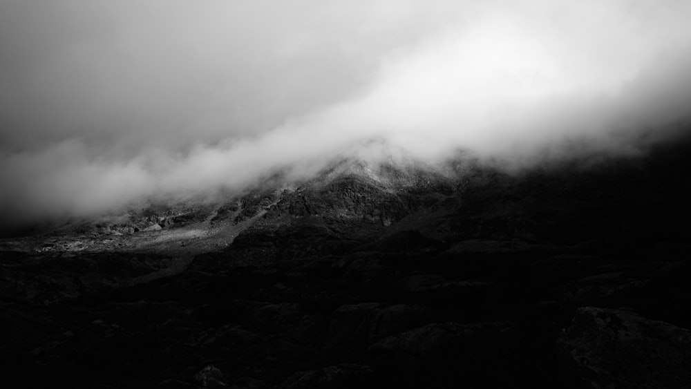 Graustufenfoto eines Berges, der von Wolken bedeckt ist