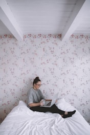 A smiling traveler using a laptop to book a hotel online in a cozy home setting.