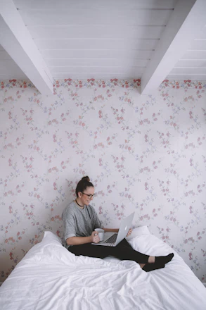 A traveler happily checking flight options on a laptop in a cozy home setting.