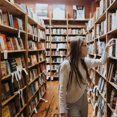 woman holding book on bookshelves