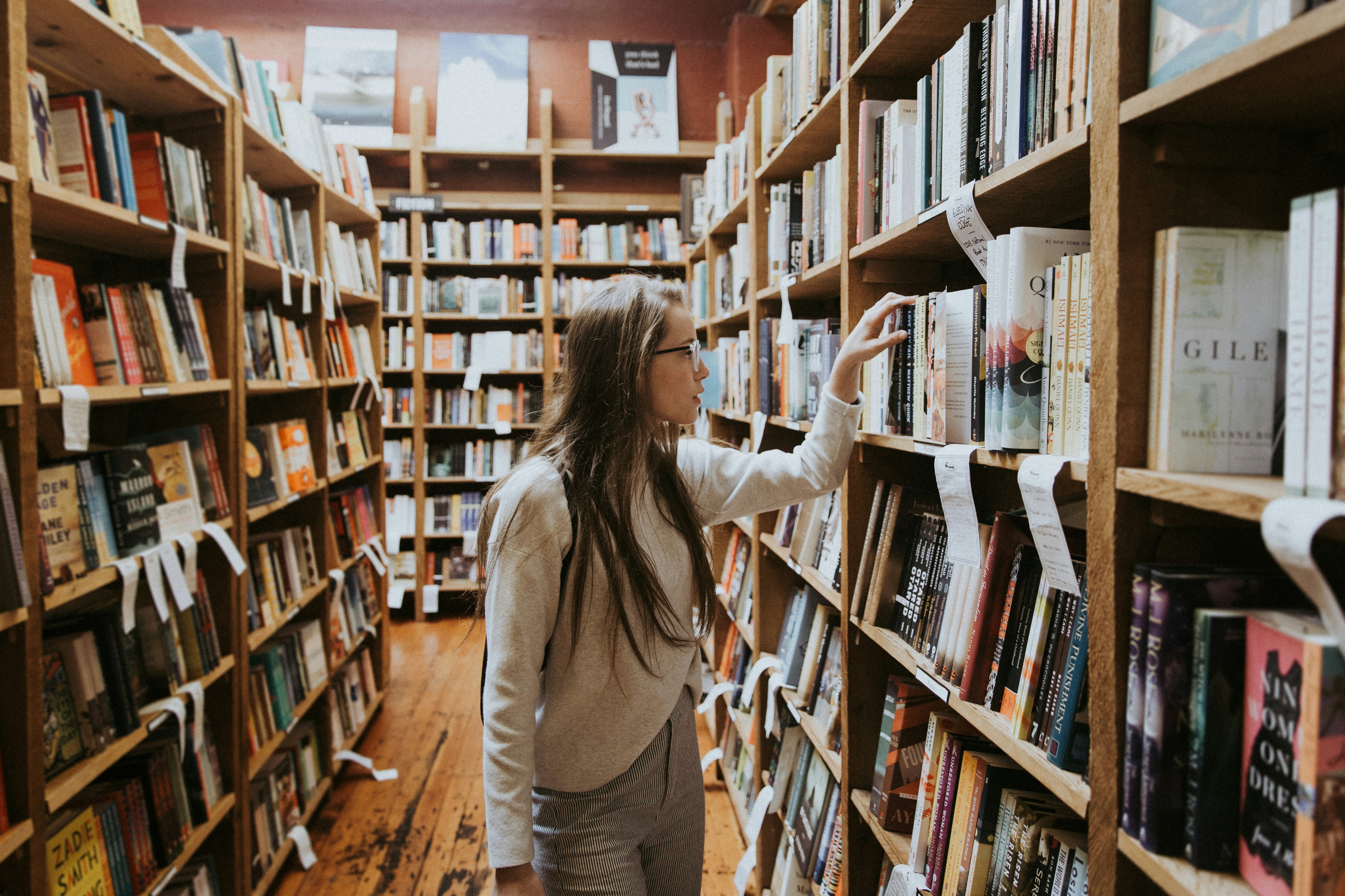 woman holding book on bookshelves