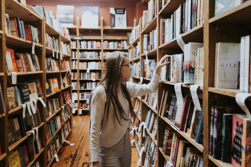 mulher segurando livro em estantes