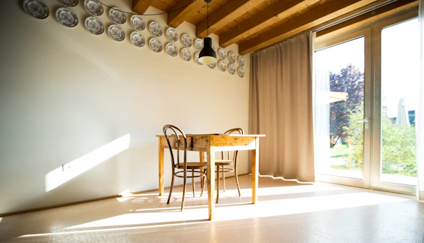 Minimalist dining area with a smooth, light oak table surrounded by comfortable chairs and a simple pendant light overhead
