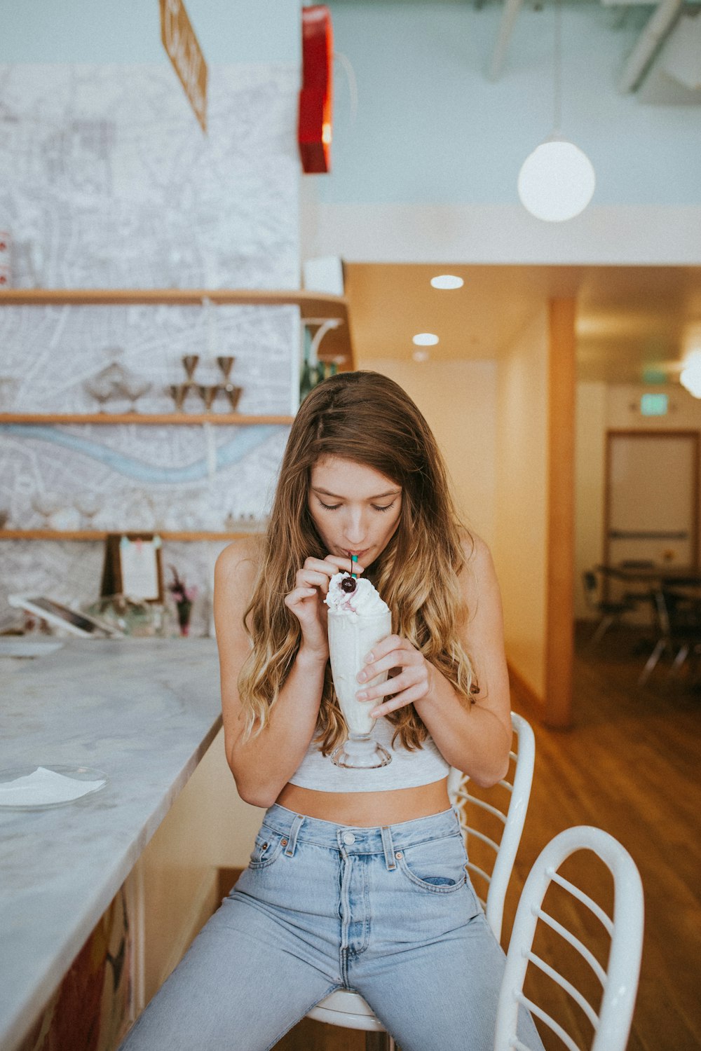 woman zipping ice cream float while sitting on chair inside room with lights turned on