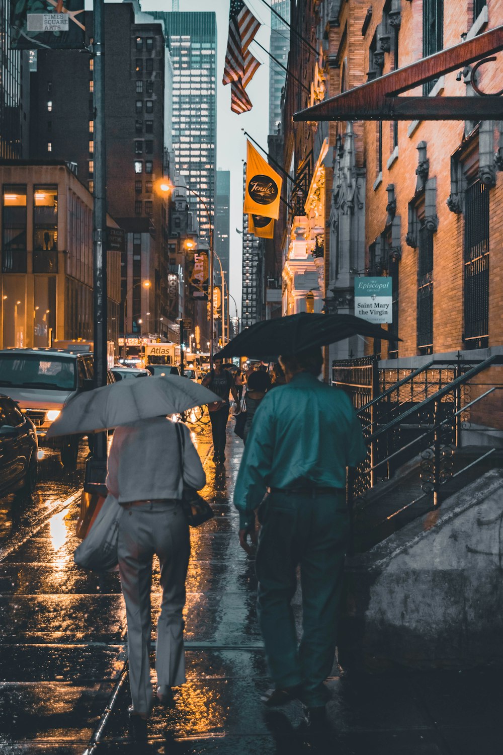 two man and woman walking near each other while holding umbrella during rain near buildings