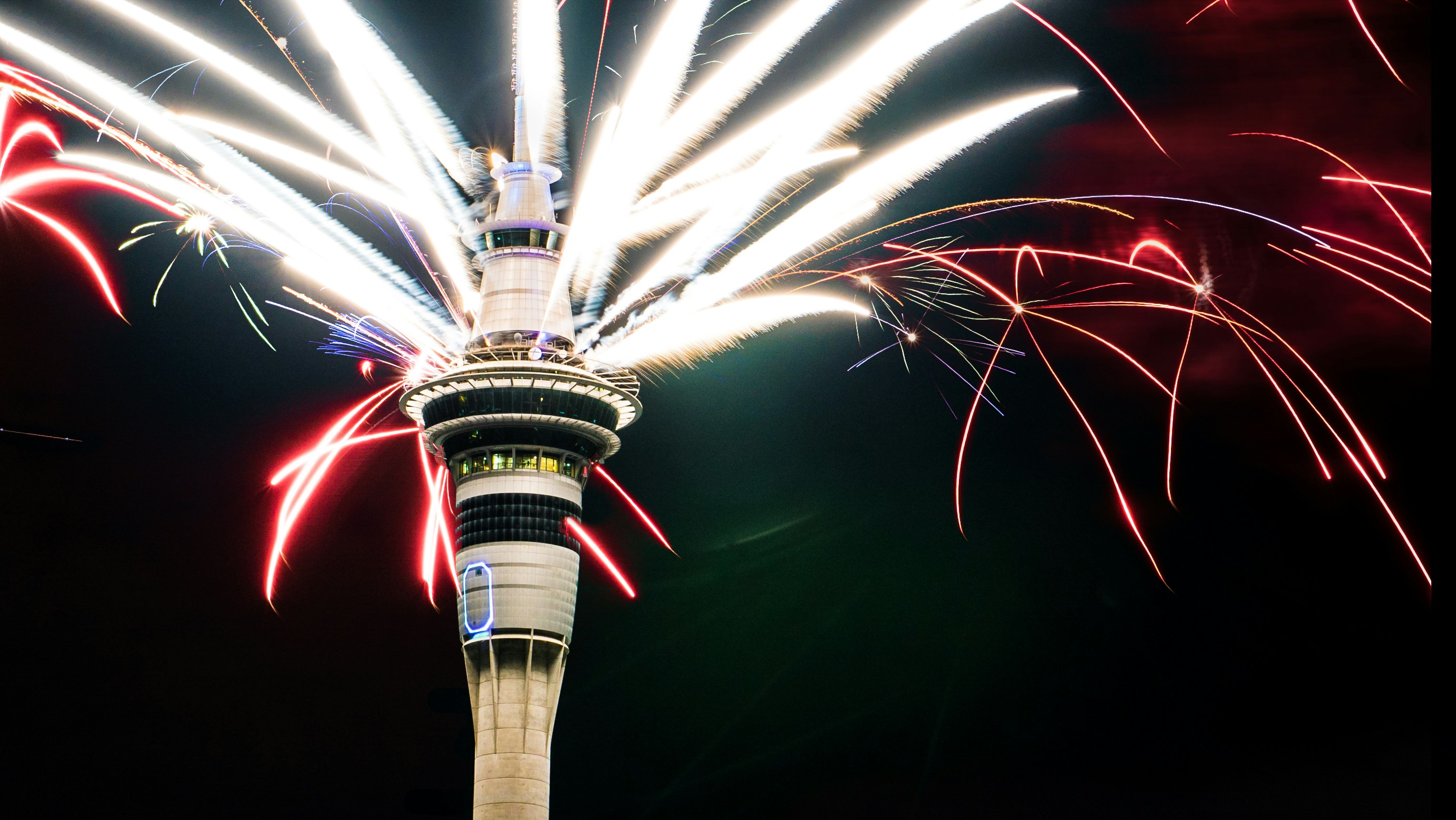 fireworks are lit up in the sky above a tower