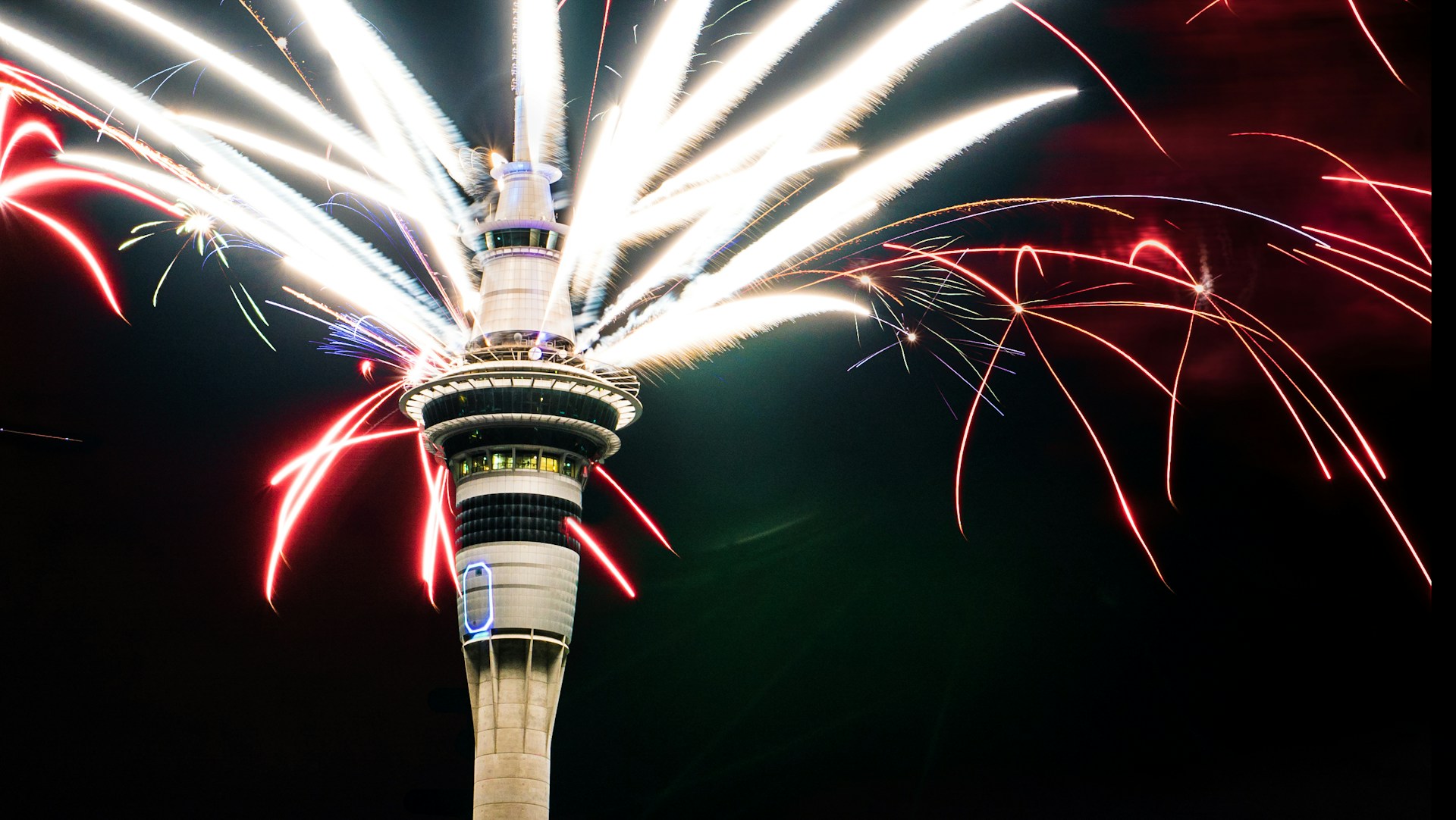 fireworks are lit up in the sky above a tower