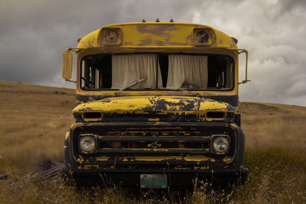 Ônibus escolar amarelo abandonado no campo de grama verde durante o dia