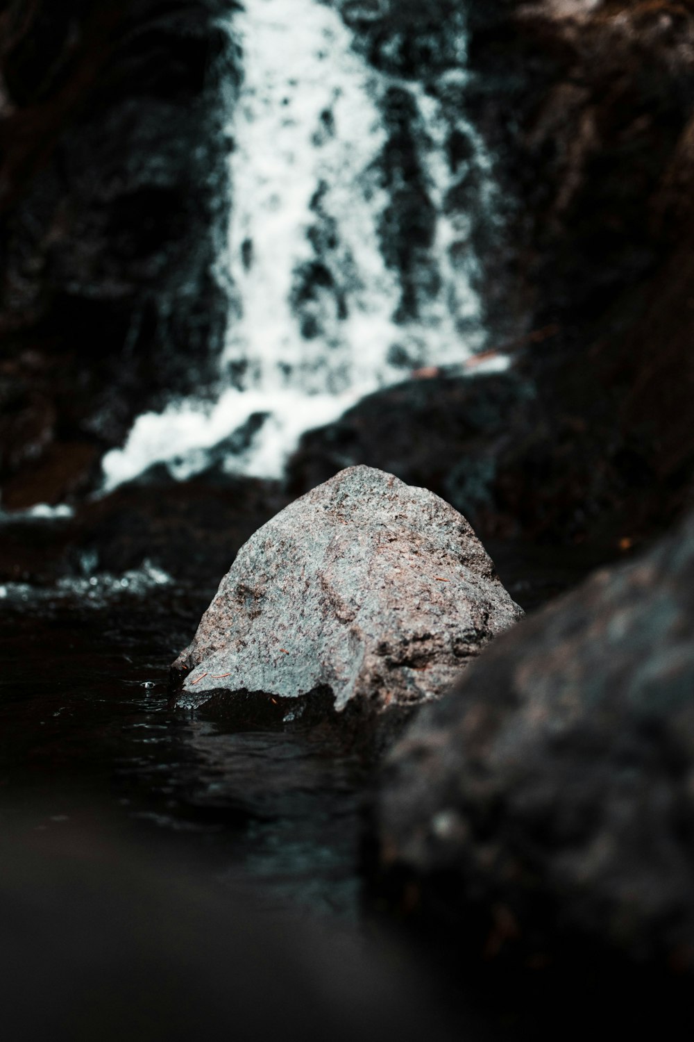 selective focus photography of gray stone in water falls