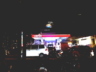 Night view of a well-lit petrol station with vehicles refueling.