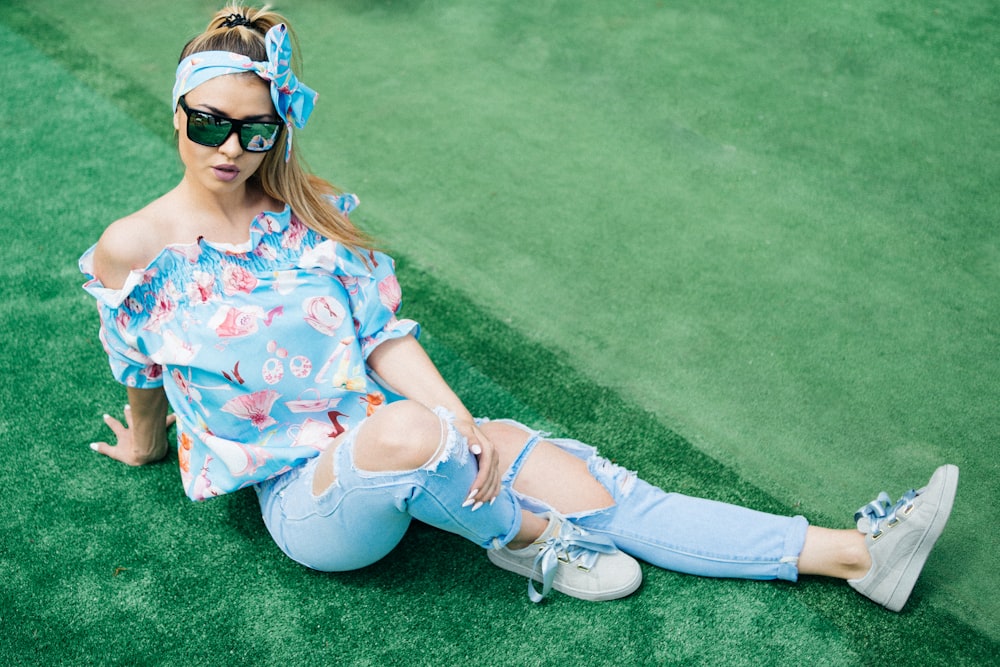 woman in blue blouse sitting on green floor