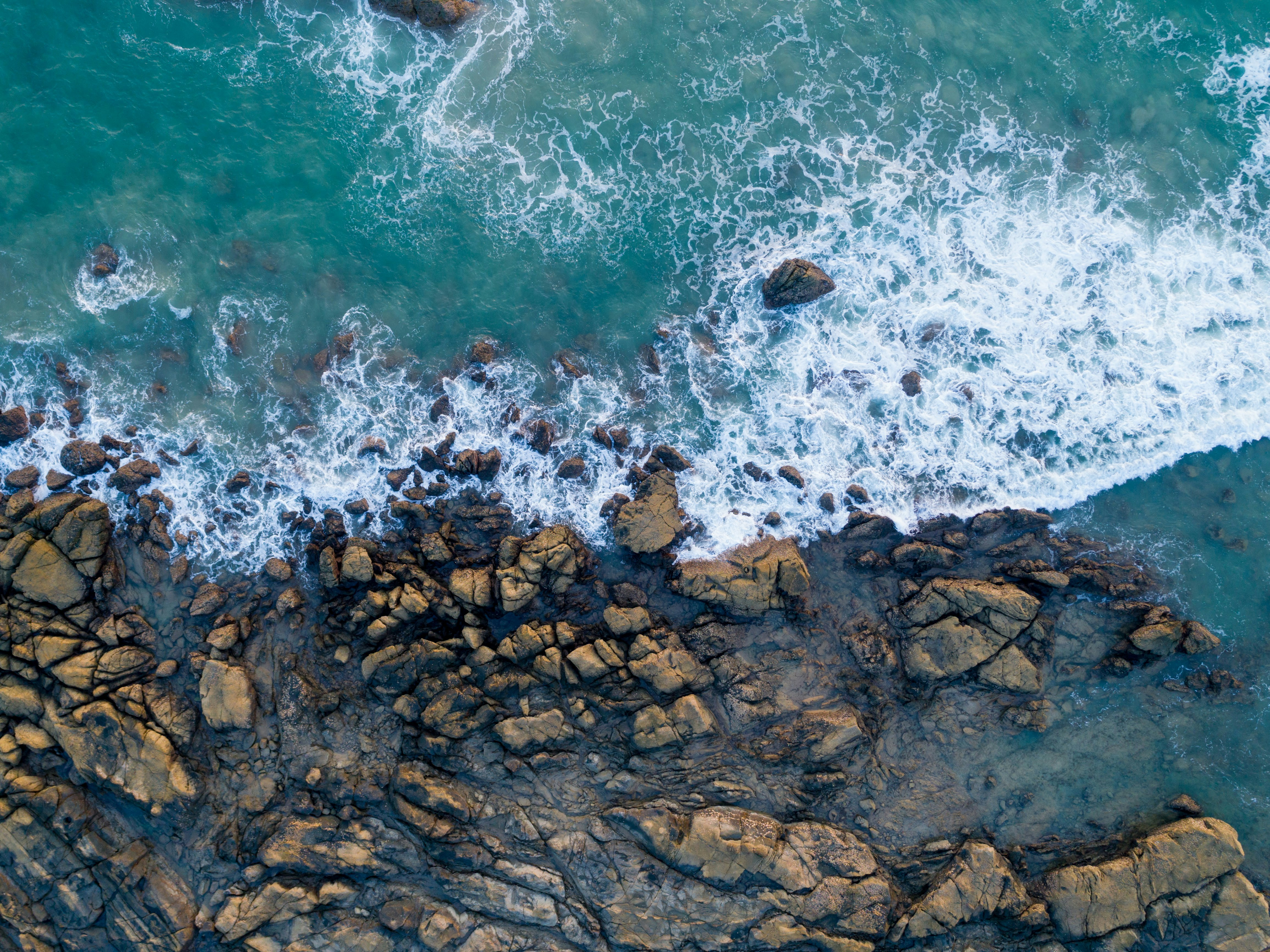 brown shore rocks with body of water, There’s not a lot of places where you can expect to see pristine clean water as the beaches in Ngapali. I had the chance to revisit Ngapali, one of the best beaches in Myanmar after roughly 10 years from my last visit and the waters still looked fantastic! Had I not traveled with my drone, I would have only been able to imagine a scene like this.