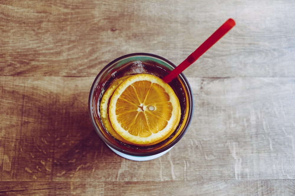 clear drinking glass filled with brown liquid and sliced oranges