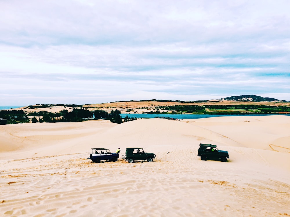 Três carros off-road em campo de areia branca durante o dia