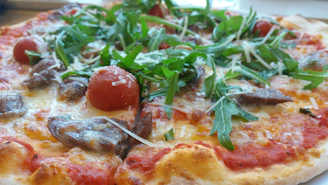 Top view of a colorful vegetarian pizza loaded with fresh tomatoes, bell peppers, olives, and arugula