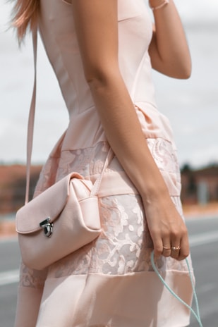 A chic woman wearing a stylish dress in a soft blush pink setting.