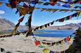 Colorful prayer flags fluttering above a serene Himalayan temple nestled among tall pine trees.