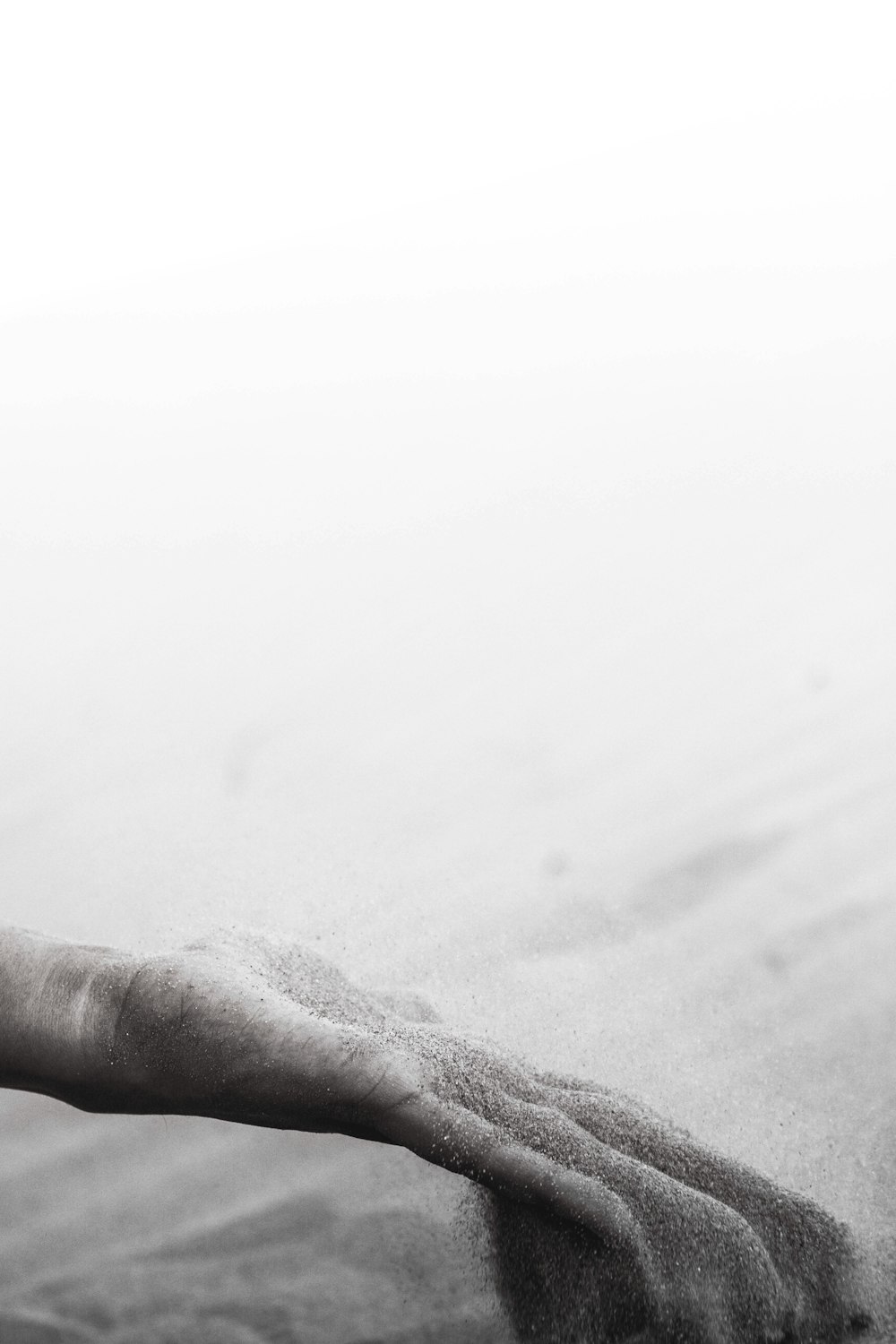 grayscale photo of person holding gray sand