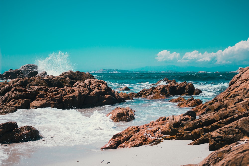 rock formation with body of water under blue sky during daytime