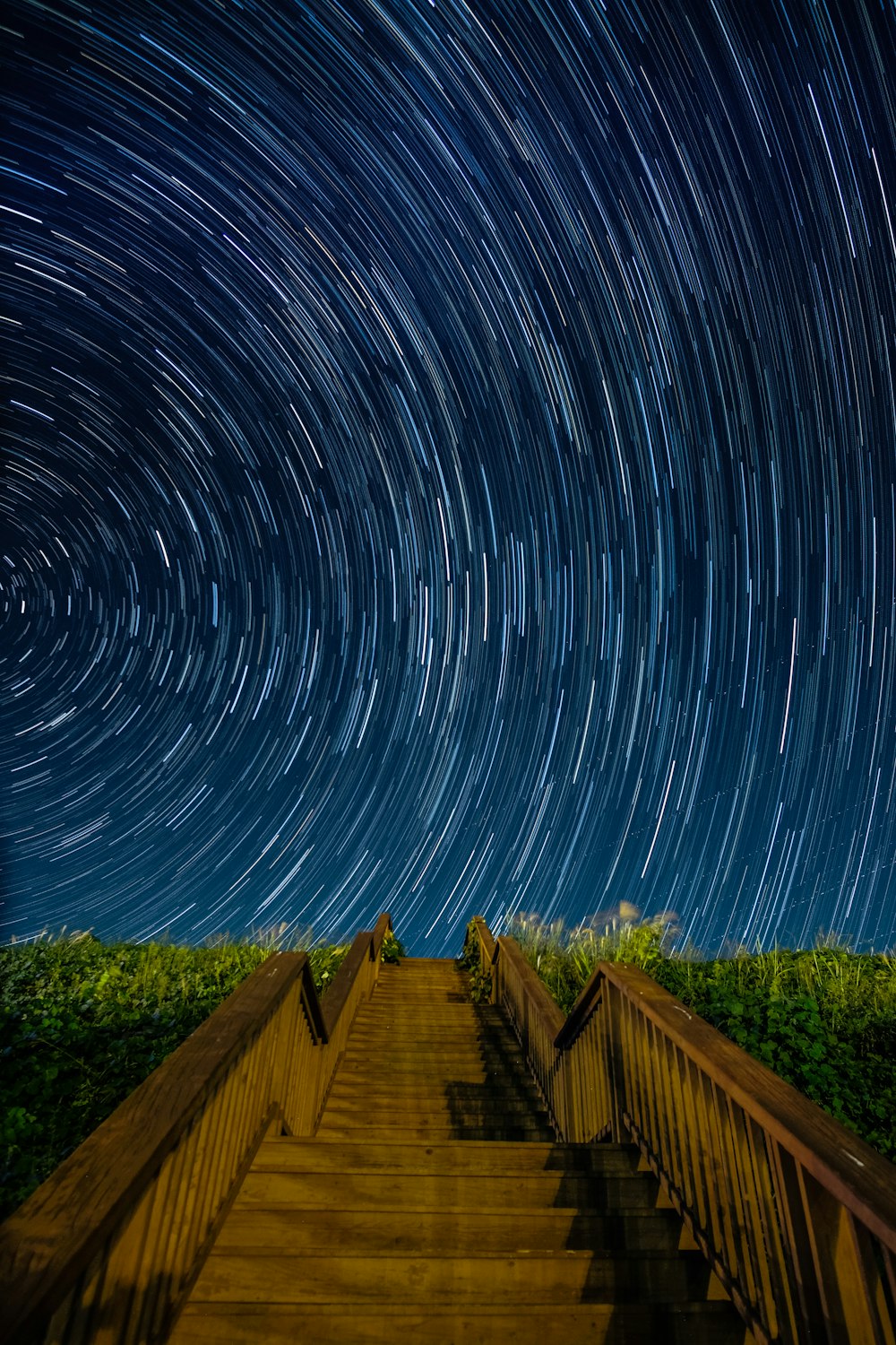 empty brown concrete stairs beside green grass under starry sky long-exposure photography