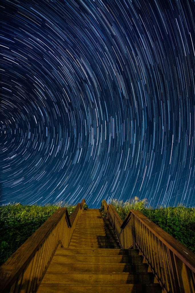 empty brown concrete stairs beside green grass under starry sky long-exposure photography