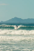 A surfer catching a perfect wave under a clear blue sky.