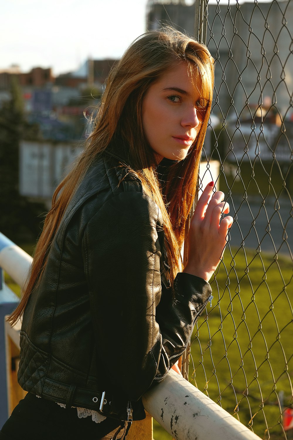 woman wearing black jacket holding fence