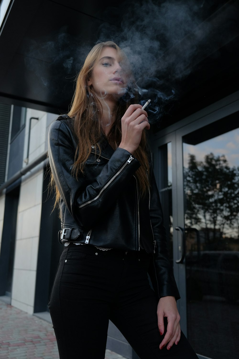 woman in black leather jacket smoking cigarette on street