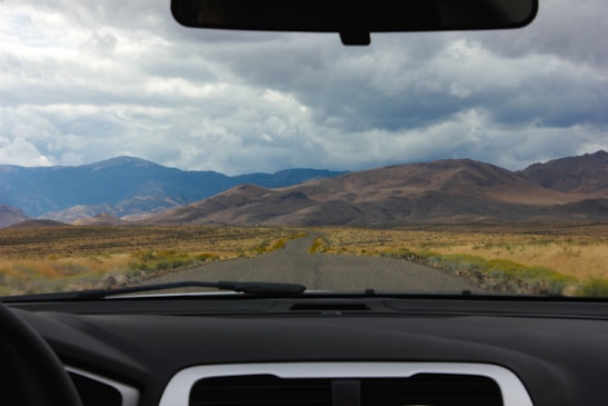 A family enjoying a road trip in a car, smiling and looking out at a beautiful landscape.